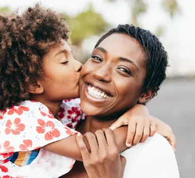 A daughter kissing a smiling mother